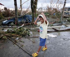 A boy walks past the devastation from powerful Typhoon Haiyan at Tacloban city, in Leyte province in central Philippines. Rescuers in the central Philippines initially counted at least 100 people dead and many more injured a day after one of the most powerful typhoons on record hit the region Nov. 8, wiping away buildings and leveling seaside homes with massive storm surges. (AP Photo/Bullit Marquez)