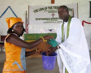 The Rev. Amos Bolay, president and bishop of the Evangelical Lutheran Church of Liberia, demonstrates the pre-Communion hand-washing technique used to help stop the spread of the Ebola virus in Liberia. (Courtesy of Amos Bolay)